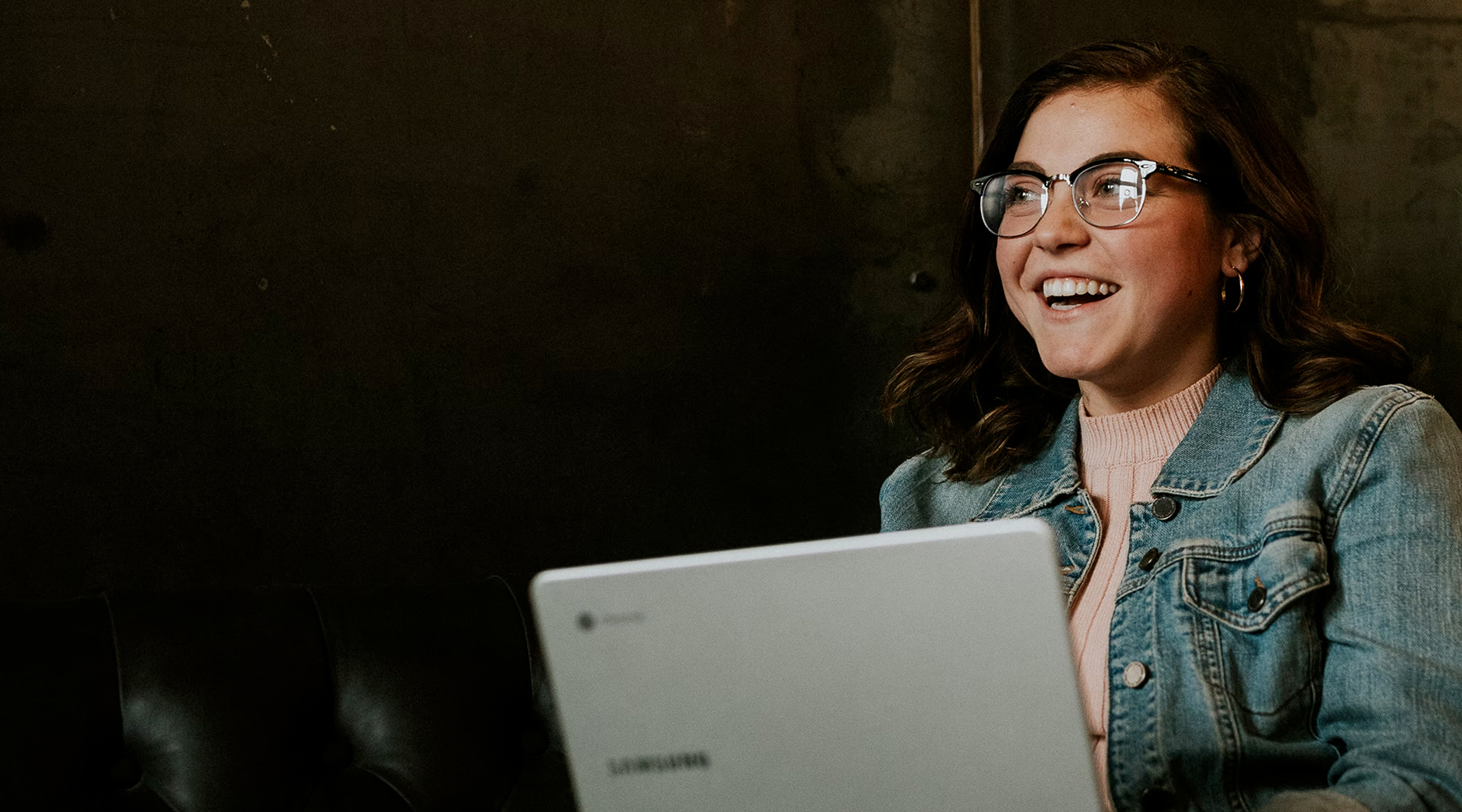 Woman with laptop sitting on couch mid-smile