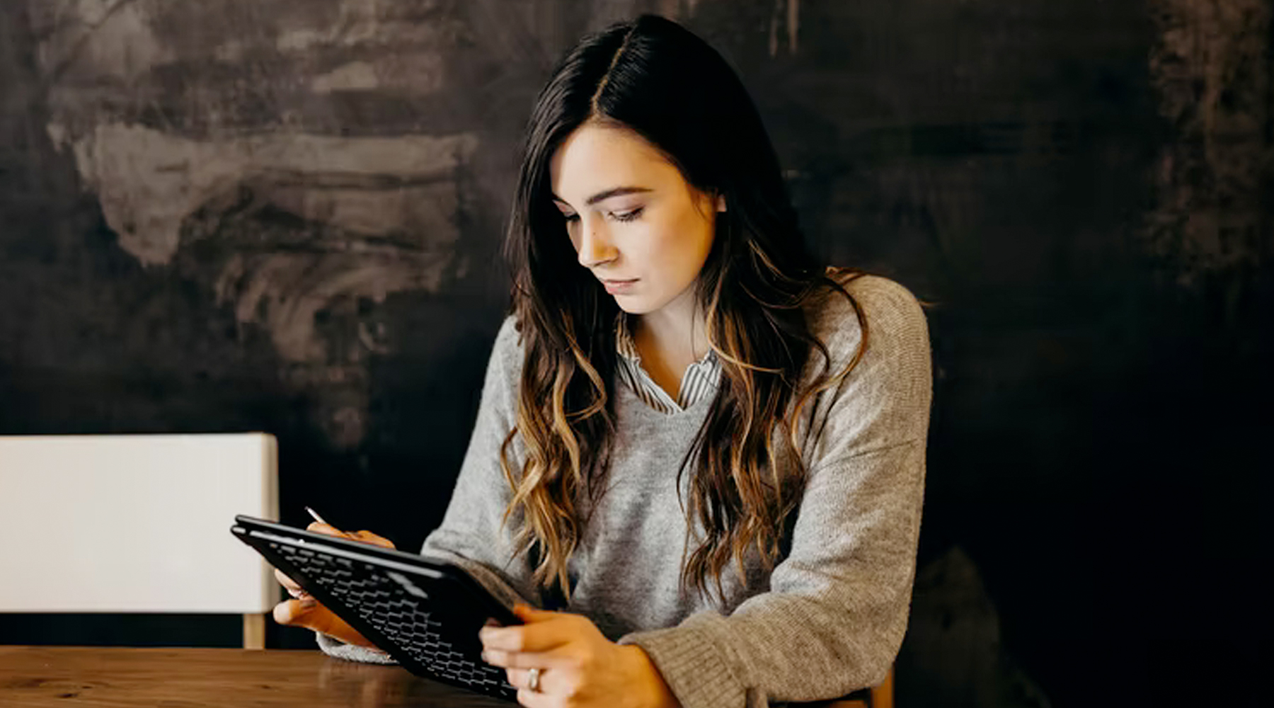 Woman at table interacting with tablet
