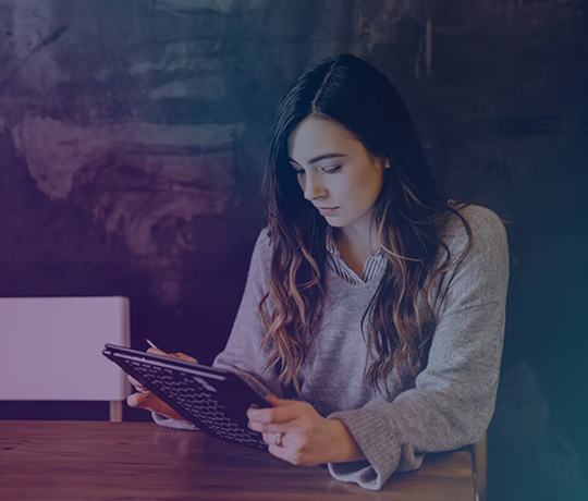 Woman at table interacting with tablet