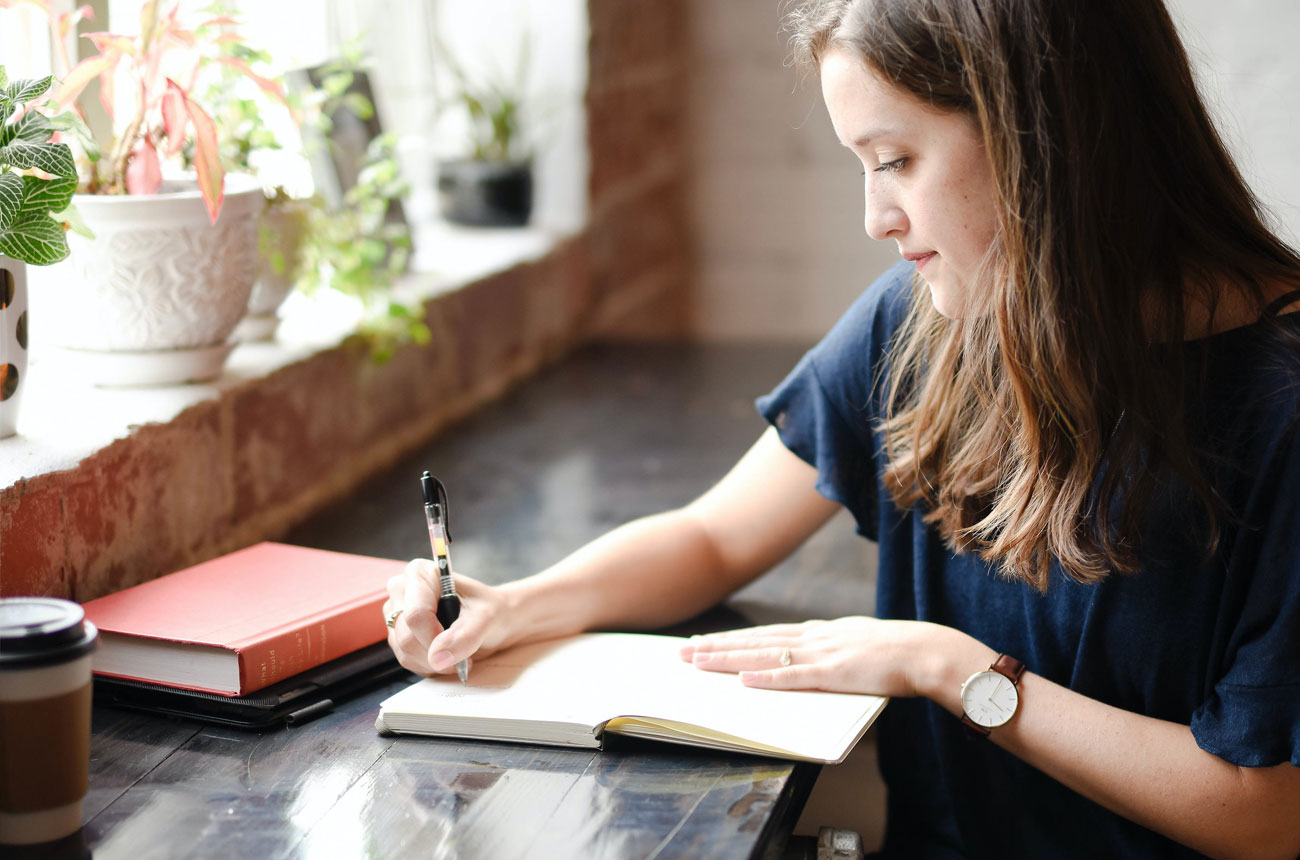 Woman writing in a notebook at a desk