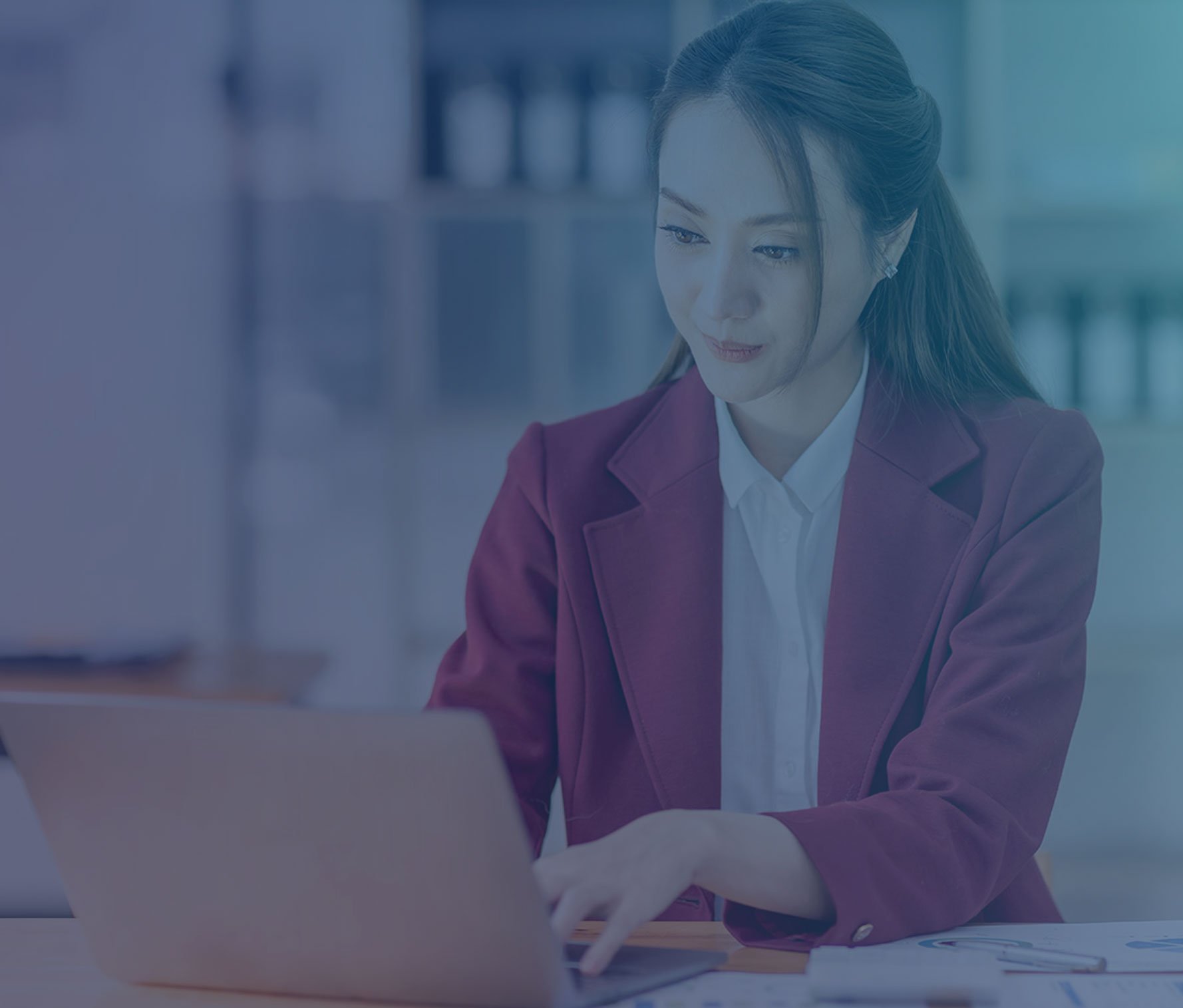 This image shows a woman sitting at her desk typing on a laptop. 